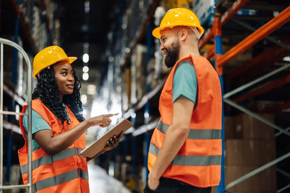 Two professionals collaborate in a warehouse, reflecting the impact of workforce development consulting on team productivity.